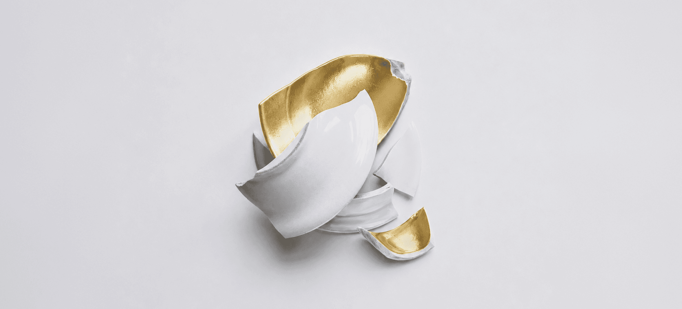 A broken white ceramic bowl with a gold interior.